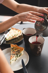 close up photo of  mug of tea and teapot in female hands. Two girlfriends drinking tea while chatting in a cafe