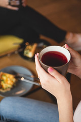 close up photo of  mug of tea and teapot in female hands. Two girlfriends drinking tea while chatting in a cafe