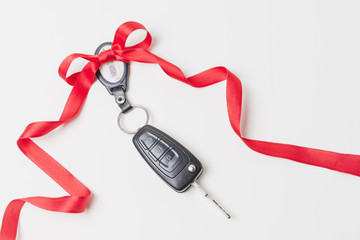 Close-up of car keys with red bow as present on white wallpaper