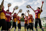 Image of woman rugby team with raised hands looking at camera