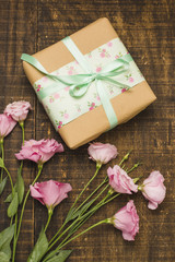 Close-up of wrapped parcel and pink fresh flower on table