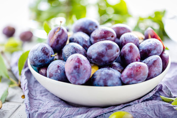 close-up view of fresh organic juicy plums in bowl on table 