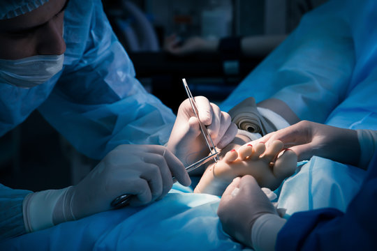 Surgeon stitches patient's leg after surgery.