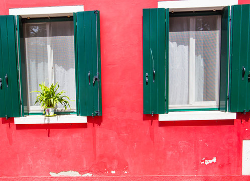 Red wall, windows, flowers, bright sunlight. Background.