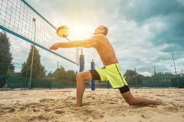 Beach Volleyball player in sunglasses in action with ball under