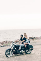 Fototapeta na wymiar young couple of bikers on black motorcycle near river