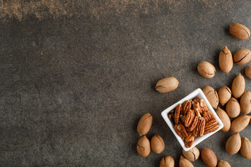 Frame of pecan nuts on marble background. Square bowl of nuts in the corner