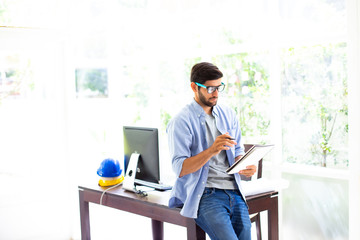 Happy Architect or engineer working in home office with computer and safety hart hat on table