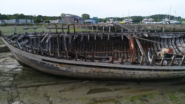 Aerial view. Skeleton of an old abandoned wooden boat. Cemetery of dead ships. The camera moves around the sides of the ship. Closeup dolly shot with drone.