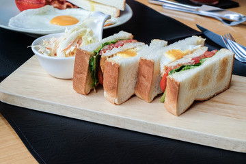English breakfast sandwich with fried eggs, sausages, bacon, chicken, toasts in the morning on the table