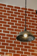 Vintage design lamp hanging from the ceiling with light on the brick wall. Soft focus with low key. Interior and object concept.
