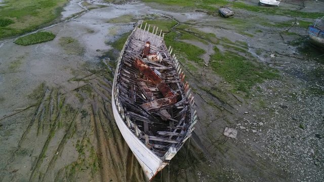 Aerial view. Skeleton of an old abandoned wooden boat. Cemetery of dead ships. Broken deserted vessel aground. Top view by drone.