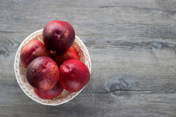Ripe organic nectarines in white basket on  gray background.