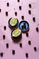 flatlay on pink background with cherries, lemons and blue porcelain plates