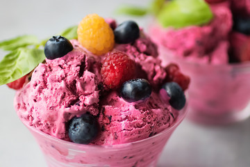 Homemade ice cream or sorbet made from fresh berries with basil in glass bowl on a gray background.