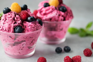 Homemade ice cream or sorbet made from fresh berries with basil in glass bowl on a gray background.