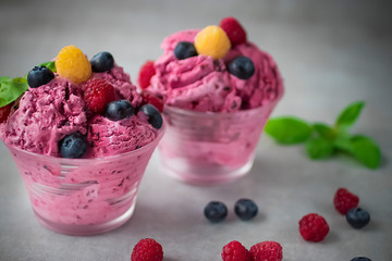 Homemade ice cream or sorbet made from fresh berries with basil in glass bowl on a gray background.