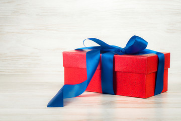 Red gift box with a blue ribbon on a background of vintage boards - Powered by Adobe