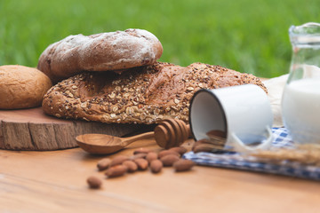 Front view of bread bun, milk, almonds and fresh milk on wooden table. Breakfast preparation, daily product.
