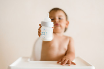 Adorable baby drinking milk from a bottle from bottle. Formula drink for infant. Kitchen