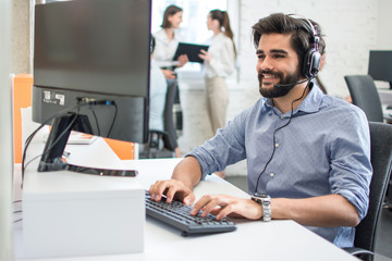 Friendly customer support service operator agent man working on computer in office