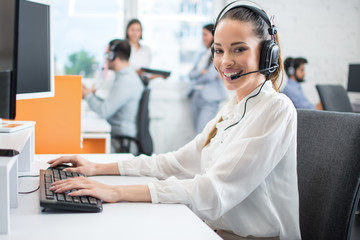 Beautiful young customer support service operator woman with headset assisting to client in call...