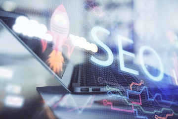 Double exposure of table with computer and seo drawing hologram. Search optimization concept.