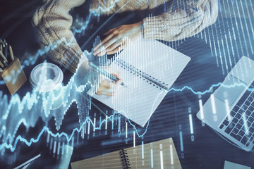 Forex graph on hand taking notes background. Concept of research. Double exposure
