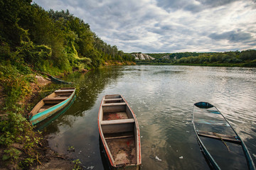 Old fishing boat near wooden jetty. Beautiful russian landscape. Sunset reflection in the water