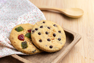 Mixed fruits cookie and Chocolate chip with wooden tray on the wood table. Delicious homemade baked cookie.