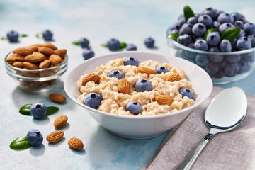 Homemade oatmeal with  fresh blueberries and almond  for breakfast on a turquoise background.