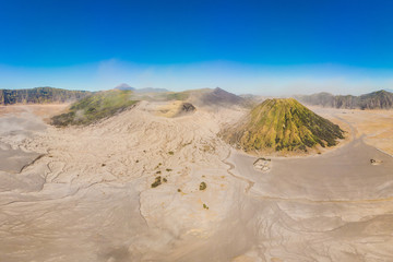 Fototapeta na wymiar Panoramic Aerial shot of the Bromo volcano and Batok volcano at the Bromo Tengger Semeru National Park on Java Island, Indonesia. One of the most famous volcanic objects in the world. Travel to