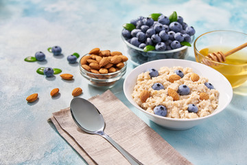 breakfast cereals with blueberries and almond  in ceramic bowl  on a turquoise background.