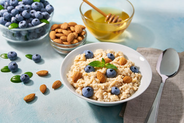 Homemade oatmeal with  fresh blueberry and organic honey for breakfast on a turquoise background.