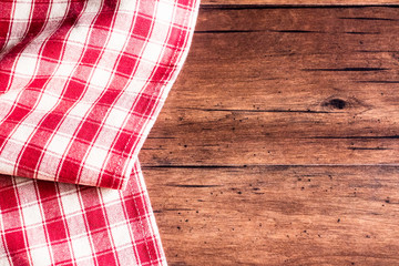Checkered red napkin on an old wooden brown background, top view. Image with copy space. Kitchen table with a towel - top view with copy space. 