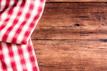 Checkered red napkin on an old wooden brown background, top view. Image with copy space. Kitchen table with a towel - top view with copy space. 