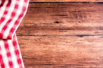 Checkered red napkin on an old wooden brown background, top view. Image with copy space. Kitchen table with a towel - top view with copy space. 