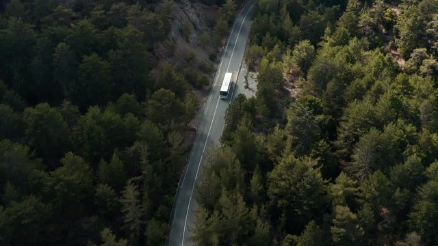Aerial drone shot of white tourist bus driving at mountain forest road in Cyprus Troodos. Left hand traffic.