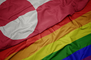 waving colorful gay rainbow flag and national flag of greenland.