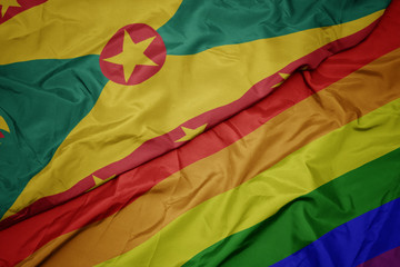 waving colorful gay rainbow flag and national flag of grenada.