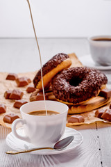 Chocolate donuts and coffee on bright wooden background
