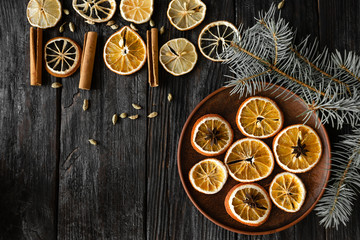 round slices of dry orange lie on a plate, Christmas tree on the table