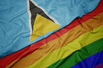 waving colorful gay rainbow flag and national flag of saint lucia.