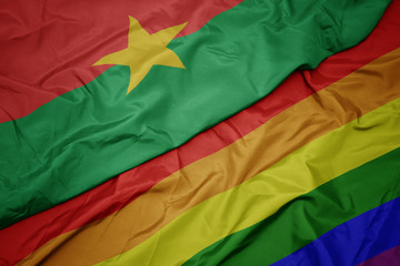 waving colorful gay rainbow flag and national flag of burkina faso.