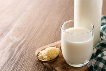 Rice milk in glass and bottle on wooden table. Copyspace