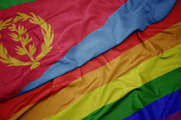 waving colorful gay rainbow flag and national flag of eritrea.