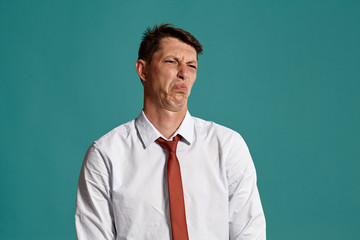 Young man in a classic white shirt and red tie posing over a blue background.