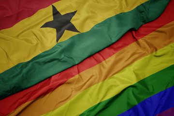 waving colorful gay rainbow flag and national flag of ghana.