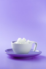 Sugar cubes in a coffee cup with violet surface