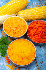 Yellow and orange gluten free diet pasta made from lentils and corn cereal on blue wooden table
